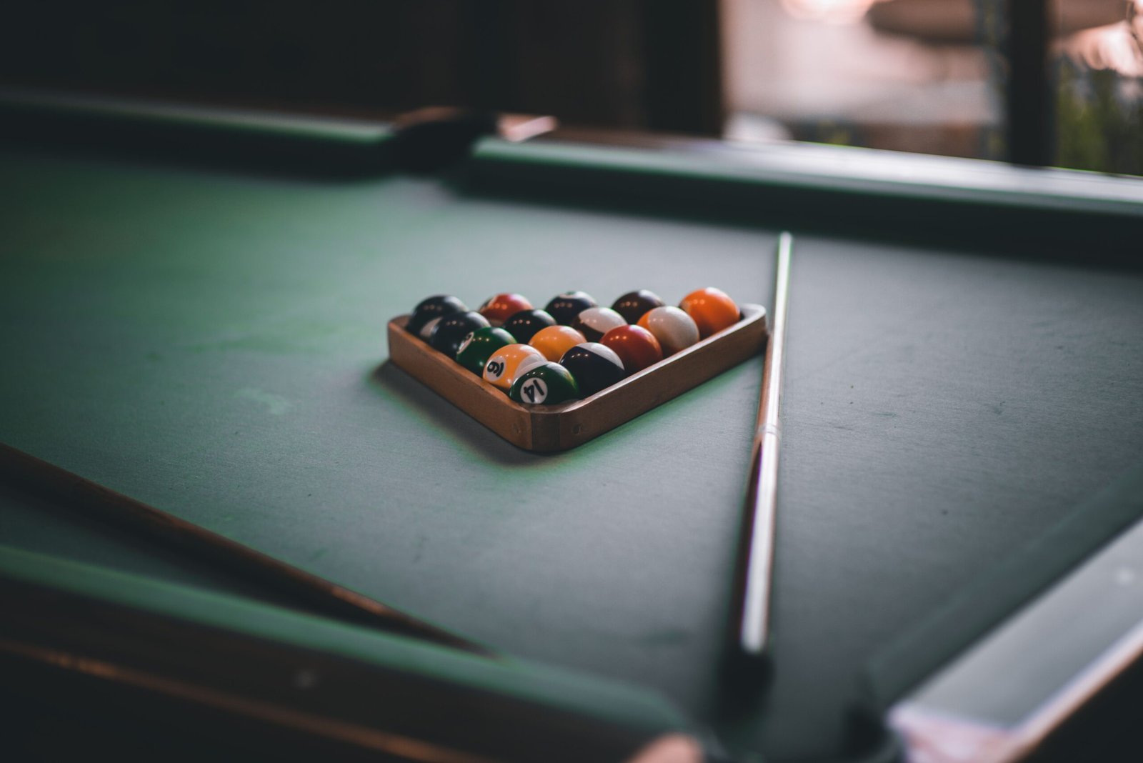 Racked pool balls and a billiard cue placed on a professional pool table before the break.